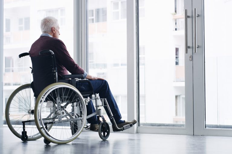 person in wheelchair looking out window