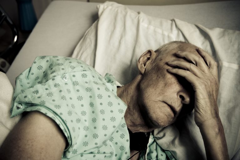 Sick and Senior Man Wearing Hospitable Gown Lying in Bed