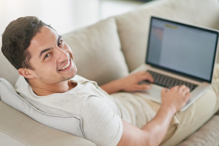 Portrait of a relaxed young man using a laptop on the sofa at home