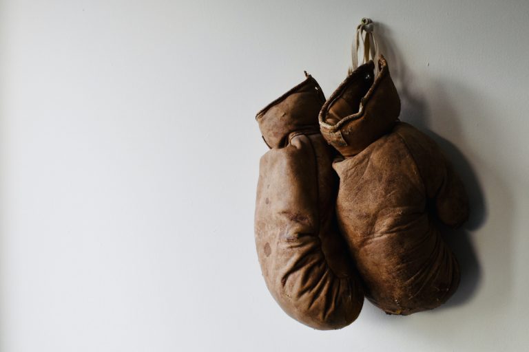 Pair of old and worn boxing gloves hang on the wall