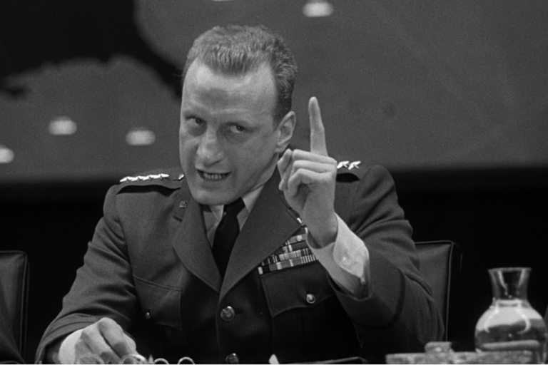 Black and white image, scene from "Dr. Strangelove." The scene shows a military general shaking his finger